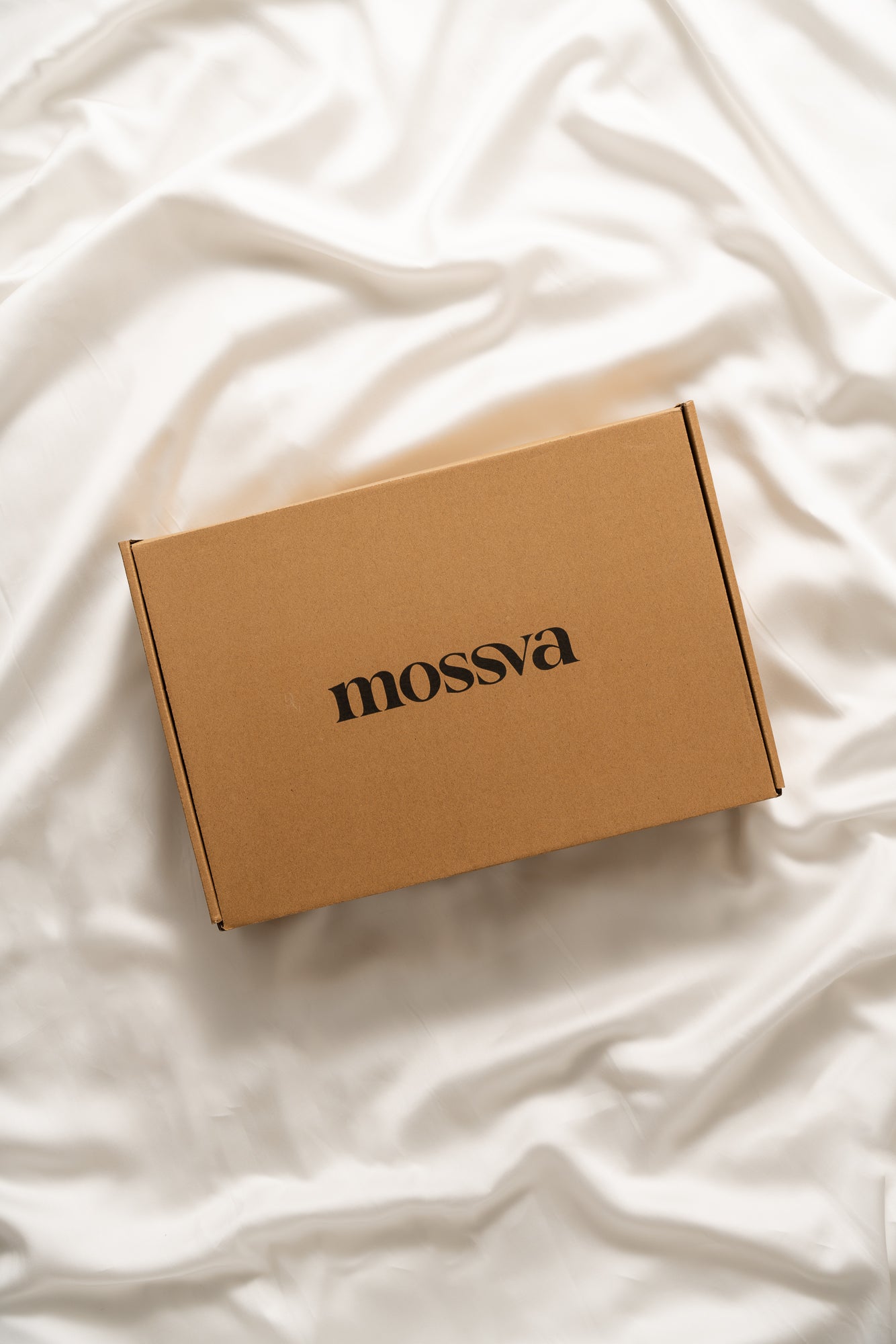 Brown box with 'mossva' branding on a white fabric background